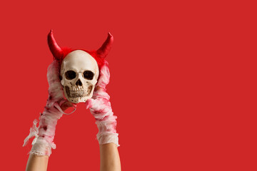 Mummy hands with skull on red background. Halloween celebration