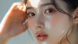 © Napasnan - Close-up of a young Asian woman gently tapping a serum into her skin, emphasizing hydration and glowing skin.