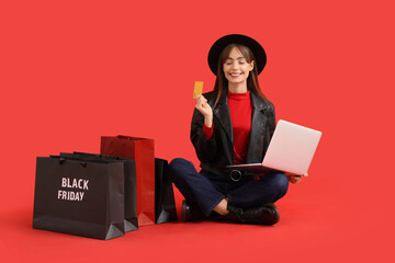 Sticker - Young woman with laptop and credit card shopping on red background. Black Friday Sale