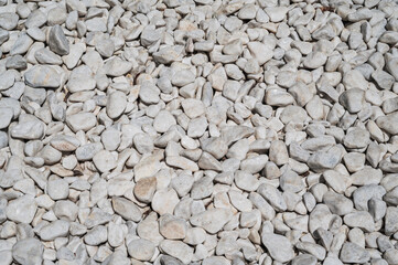 pattern of white pebbles, surfaces of white and gray gravel, natural stone floor in the garden, texture of stone materials, abstract background.