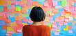 © Sweetrose official  - Back view of a thoughtful woman looking at sticky notes on wall in the office, a woman on the background of a wall of stickers, Creative brainstorming session with colorful sticky notes on glass.