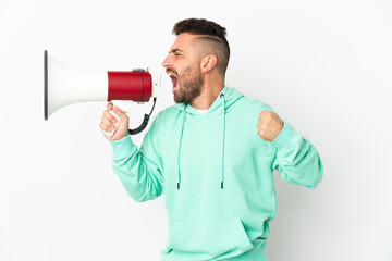 Caucasian man isolated on white background shouting through a megaphone to announce something in lateral position