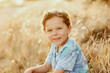 © Austockphoto - Happy little boy sitting in long dry grass in golden afternoon light