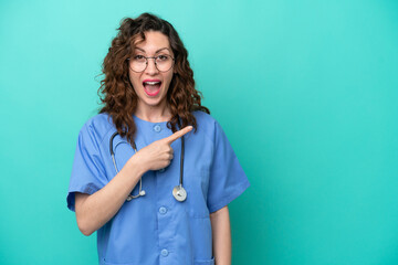 Young nurse caucasian woman isolated on blue background surprised and pointing side