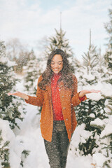 A young woman throwing snow on a sunny cold winter day. 