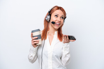 Telemarketer Russian girl working with a headset isolated on white background holding coffee to take away and a mobile