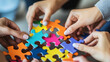 © thanakrit - A group of hands assembling colorful puzzle pieces, highlighting collaboration and teamwork in a vibrant setting.