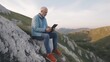 © AnKriya - Senior Man Using Tablet on Rocky Mountaintop � Peaceful and Natural Setting