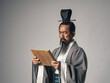 © metamorworks - 三国志に登場する諸葛孔明のような中国歴史上の人物が竹簡に書かれた文字を読むシーン