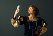 © primipil - Portrait of a young aristocratic woman doing photo selfie with mobile phone and dressed in a medieval dress