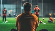 © Galib - A man sits on the sideline watching a soccer game.