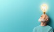 © Autaporn - An elderly man with a thoughtful expression and a glowing light bulb above his head, symbolizing creativity and ideas.