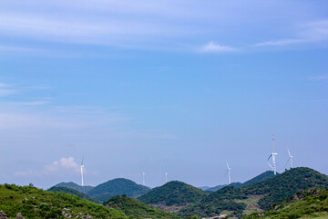 Wind turbines standing on the green prairie represent green environmental protection, sustainable development and protecting the earth