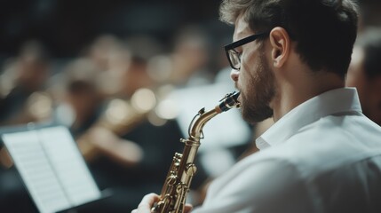 A saxophonist wearing a white shirt is deeply immersed in music during an orchestral session, highlighting his dedication and the blurred background embodies the energy of the scene.