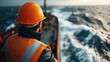© JoxyAimages - A worker in safety gear stands on the deck of a ship, observing the turbulent ocean waves and ensuring safety procedures are followed during maritime operations.