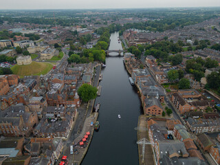 Panorama of historic York city, UK. Aerial view towards Skeldergate Bridge, Clifford's Tower and York castle. Above River Ouse with waterfront pub terrace on a cloudy day.