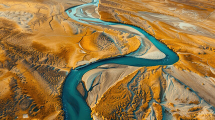 Wall Mural - Aerial view of a winding river cutting through a desert, creating abstract, serpentine patterns in the sand, with contrasting colors of blue water and golden dunes