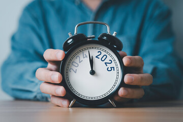 Wall Mural - businessman holding 2024 and 2025 on black alarm clock for preparation of merry christmas and happy 