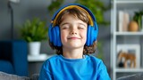 A happy little boy listens to music, headphones wrapped around him as he smiles.