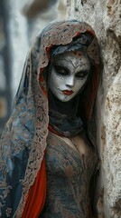 Standing on a stone wall is a masked woman dressed elaborately for the Venetian carnival.