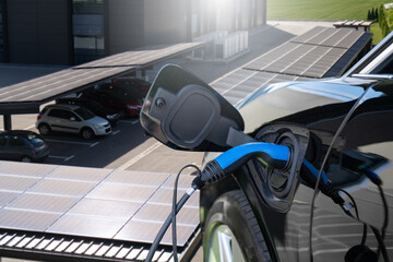 Wall Mural - Electric car is charging from a charging station that takes energy from solar panels. Close up.