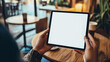 © Elnare - Close up of a person holding a tablet with a blank white screen in a cafe.