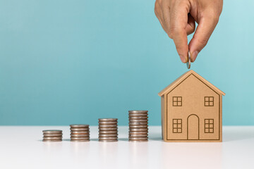 Money saving, real estate investment, investing for home lone. A man putting coin to house money box for saving money to buy a house