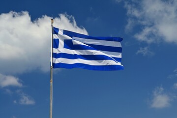 Flag of Greece Flying in Wind and Blue Sky. Summer background for travel and holidays.