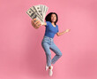 © Prostock-studio - Full length portrait of a joyful young asian woman jumping up high and holding bunch of money banknotes, showing close to camera, celebrating win, isolated over pink studio background, collage