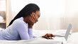 © Prostock-studio - Relaxed Black Woman Using Laptop Browsing Internet Lying In Bed At Home On Weekend. Selective Focus