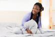 © Prostock-studio - Good Morning Concept. Happy Black Girl Smiling At Camera Sitting In Bed In Bedroom Rested After Sleeping In Comfortable Bed.
