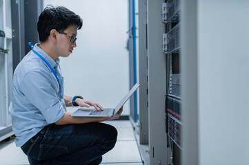 Computer engineer is setting up network in server room,Systems Maintenance Technician,Male engineer working in server room at modern data center