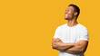© Prostock-studio - Full Of Joy. Happy african american guy looking aside at copyspace with crossed arms folded, panorama