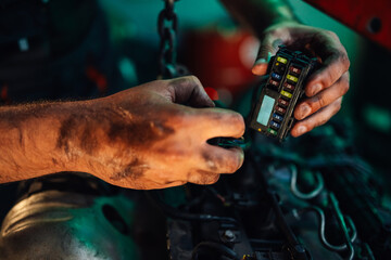 Close-up hands of a mechanic examining a fuse box in an engine