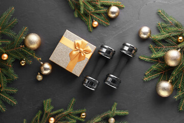 Wall Mural - Dumbbells, gift box and Christmas decor on black background, flat lay