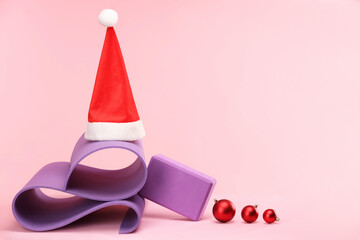 Poster - Yoga mat, Santa hat and baubles on pink background, space for text