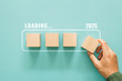 © sichon - New year 2025 countdown, goal planning, Loading year 2025, Merry christmas and happy new year. Hand putting wooden cube for countdown to 2025 with download ba