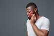 © Prostock-studio - Upset black guy suffering from strong pulpitis, white studio background, touching highlighted with red cheek, copy space