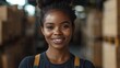 © FATNA - A smiling African female factory worker standing in warehouse.
