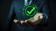 © Pannin - Holographic image of a green compliance tick in the hand of a business executive. Concept for audits, certifications, or green initiatives.
