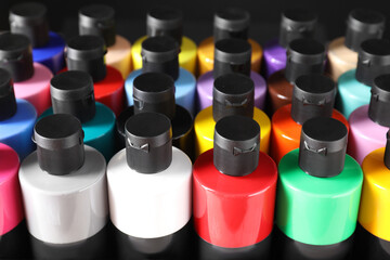 Wall Mural - Acrylic paints of different colors in bottles against black background, closeup