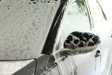 Wall Mural - Auto covered with cleaning foam at car wash, closeup