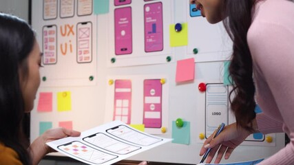 Two asian women working as ux ui designers, collaborating and brainstorming on a new mobile application interface wireframe design