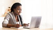 © Prostock-studio - Smiling Black Businesswoman Working On Laptop And Taking Notes In Modern Office. Free Space For Your Text