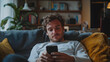© StockSavant - Happy Handsome Caucasian Man Using Smartphone in Cozy Living Room at Home. Man Resting on Comfortable Sofa. He's Browsing the Internet and Checking Videos on Social Networks and Having Fun