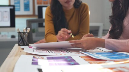 Wall Mural - two ux designers engage in a discussion about mobile application interface sketches laid out on a de
