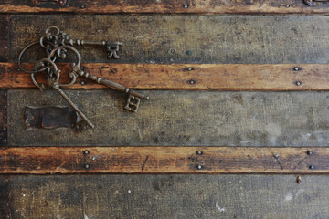 A top view image of three vintage metal keys on a grunge wooden background.