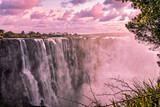 Majestic waterfall cascading under a serene sunset sky.