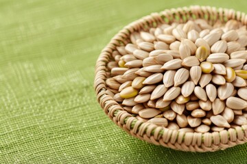 Close-up of a wicker basket filled with sunflower seeds on a green textured background. Healthy snack, natural food concept.