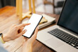 © Rymden - Mockup image of a woman using smartphone with blank screen on wooden table